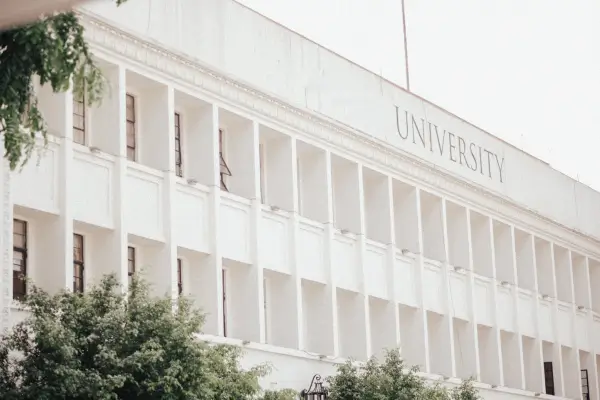 Vista de um edifício universitário branco com destaque para a fachada e a inscrição UNIVERSIDADE.